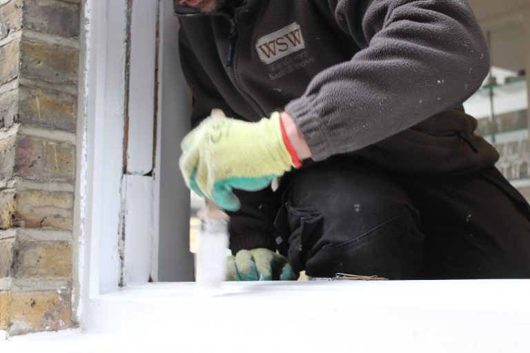 Workman restoring the paint on sash windows