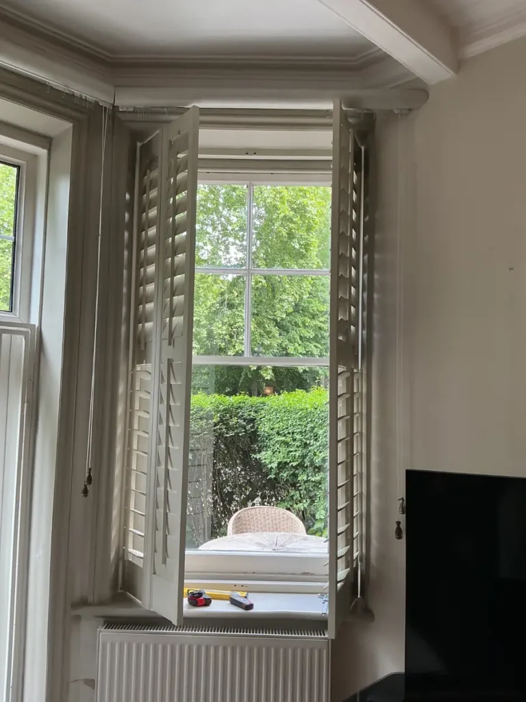 Original sash window with plantation shutters before sash replacement, Battersea